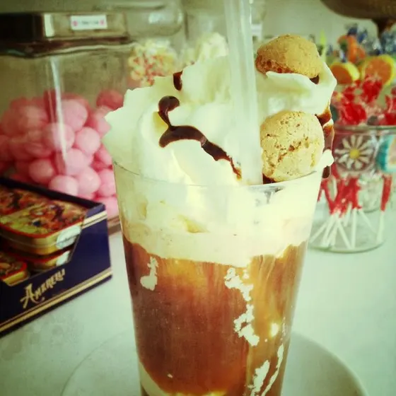 Ein Eiskaffee im hohen Glas mit Sahnehaube und Amarettini